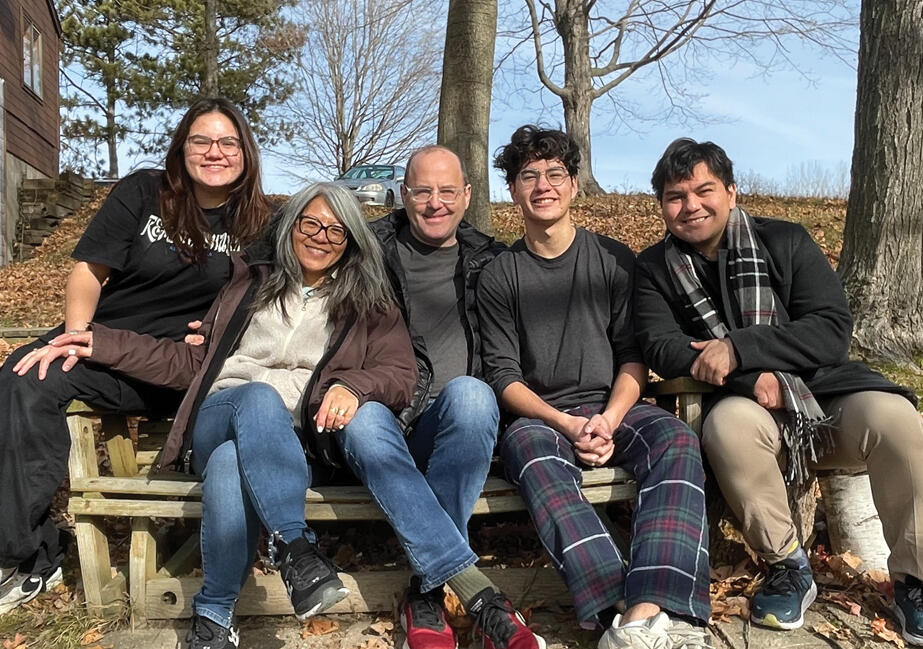 Leni and her family on a bench with blue skies behind them